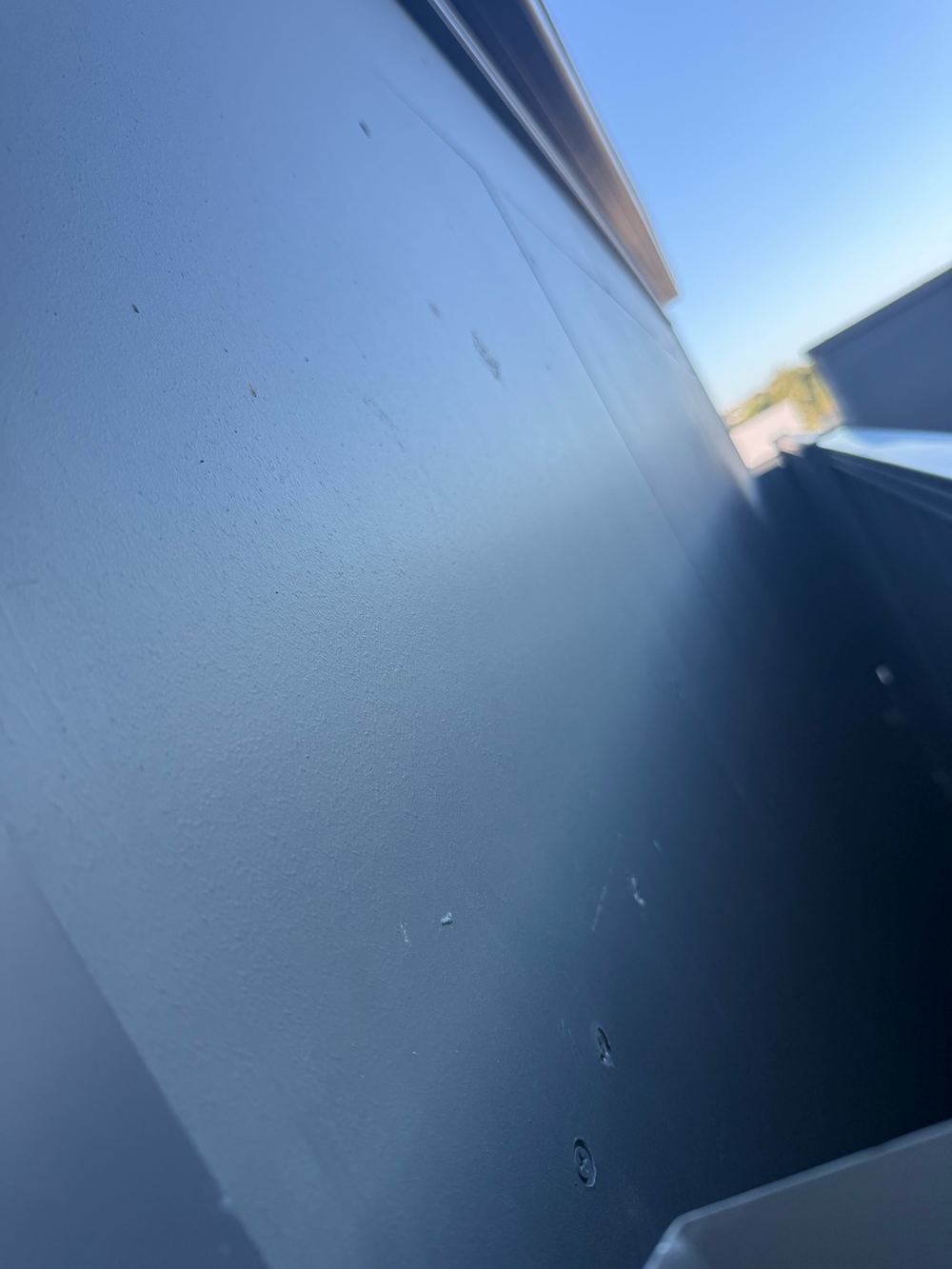 Boundary wall cladding left with exposed fixings and open holes, found during a pre-handover inspection in Pakenham