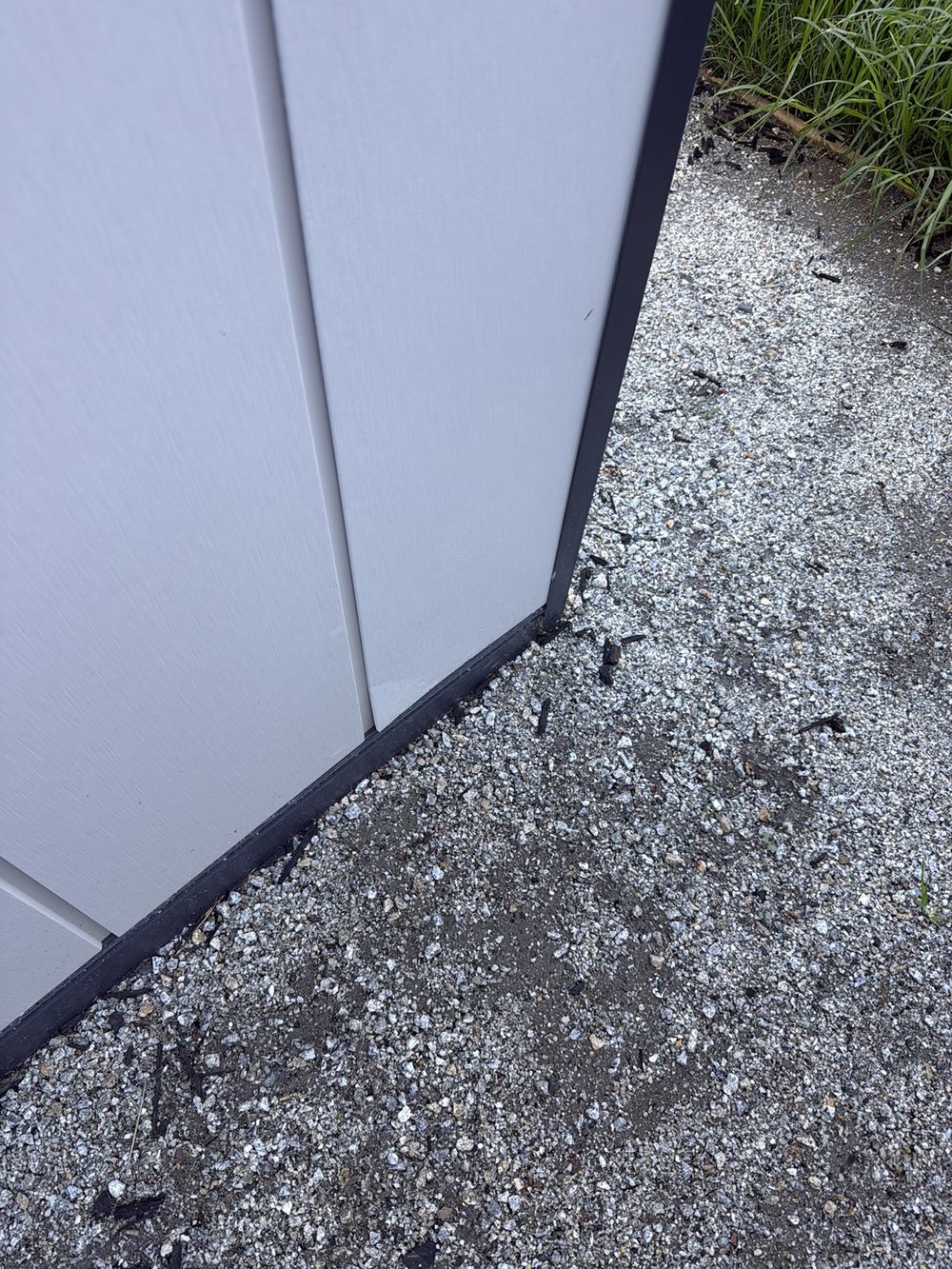 Damaged cladding panel edge near ground level, exposed to moisture, found during a pre-handover inspection in Pakenham